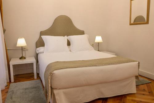 1 dormitorio con 1 cama blanca grande y 2 lámparas en Hospederia Seminario Conciliar de San Julián, en Cuenca