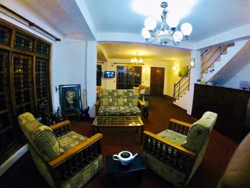 a living room with a couch and chairs and a chandelier at New Royal Mount Hotel in Nuwara Eliya
