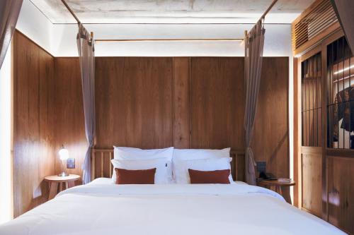 a bedroom with a large white bed with wooden walls at Hotel Gahn Khao Lak in Khao Lak