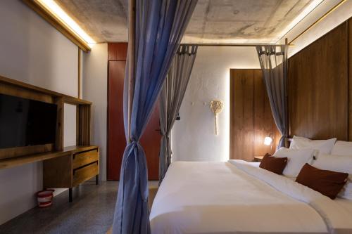 a bedroom with a large bed and a television at Hotel Gahn Khao Lak in Khao Lak