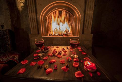 a table with two glasses of wine next to a fireplace at Karamanli Konagi in Guzelyurt