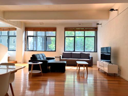 a living room with a couch and a tv at ReadySet Apartments on King in Melbourne