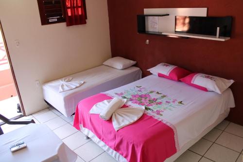 two beds in a room with pink and white at Pousada Pé de Serra Baturité in Baturité