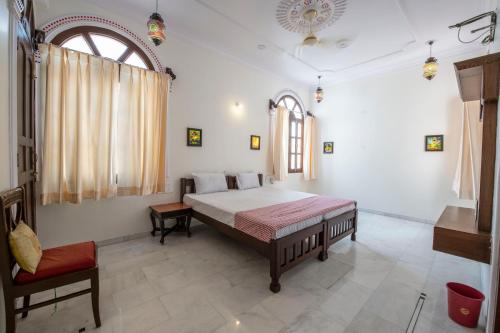 a bedroom with a large bed and a chair at Jashoda Mystic Haveli in Pushkar