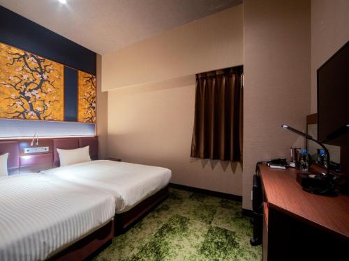 a hotel room with a large bed and a desk at Hotel Halrotto Fukuoka Hakata in Fukuoka