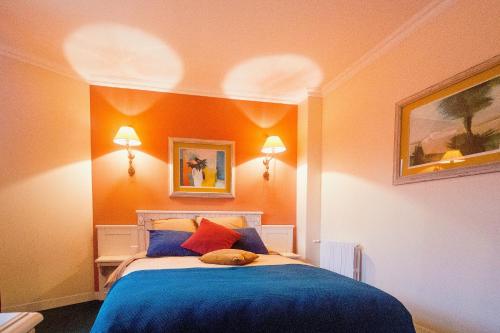 a bedroom with a bed with blue sheets and orange walls at ARTEMIS SUITE in Barbizon