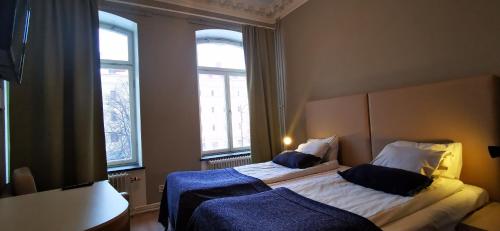 a bedroom with two beds and two windows at Sundsvall City Hotel in Sundsvall