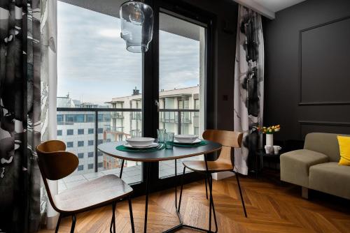 a table and chairs in a room with a large window at Apartments Konstruktorska by Renters Prestige in Warsaw