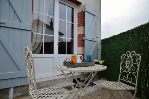 einen Tisch und zwei Stühle auf einer Terrasse in der Unterkunft Le Tacot in Pont-de-Poitte