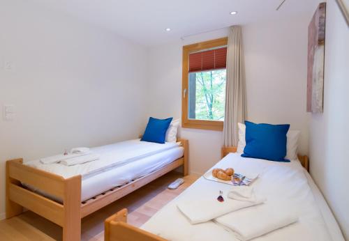 twee bedden in een kamer met blauwe kussens bij Chalet Waldschluecht in Wengen