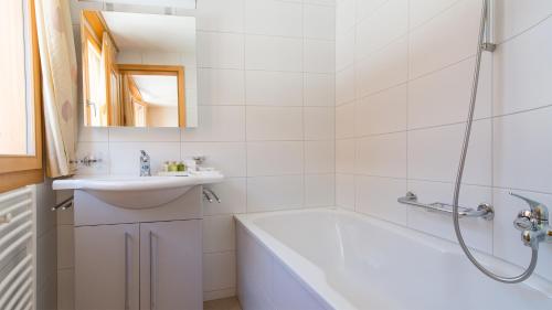 a white bathroom with a tub and a sink at Chalet Luna in Wengen