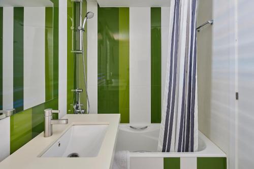 a green and white bathroom with a sink and a shower at Apartamentos en Rocamaura in L'Estartit