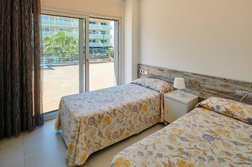 2 camas en una habitación de hotel con ventana en Apartamentos en Rocamaura, en L'Estartit