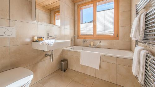 a bathroom with a tub and a sink and a toilet at Chalet Luna in Wengen
