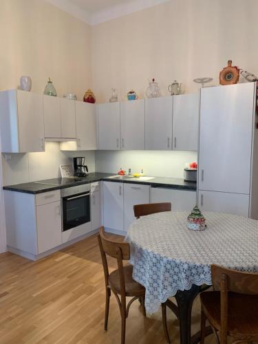 a kitchen with white cabinets and a table with chairs at Villa Pazelt Top2 in Bad Vöslau