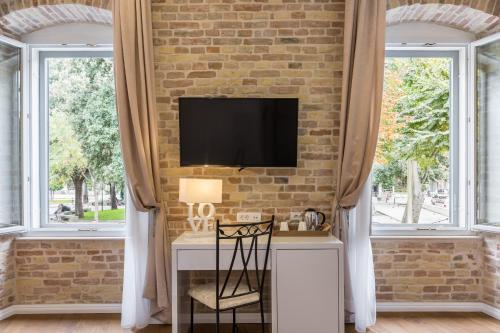 a room with a desk with a tv on a brick wall at Pellegrini Luxury Rooms in Split