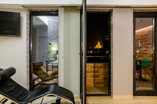 a room with sliding glass doors and a chair at Boutique Apart Upe in Tbilisi City
