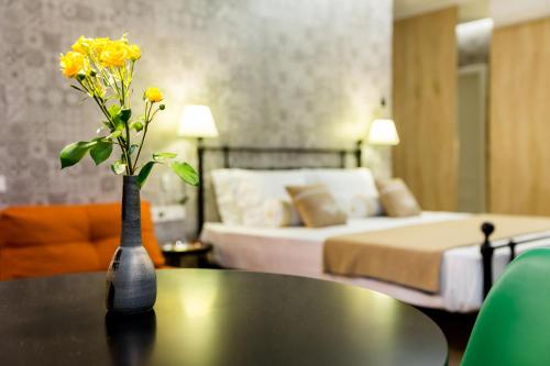a vase with yellow flowers on a table in a bedroom at Boutique Apart Upe in Tbilisi City