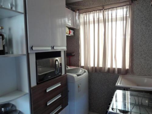 una pequeña cocina con fregadero y microondas en Apartamento na Praia, en Ilhéus