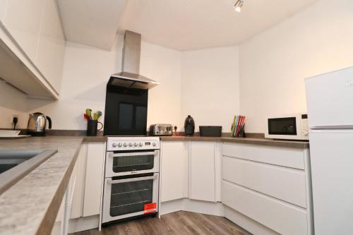 a kitchen with white cabinets and a stove top oven at TOWN CENTRE apartment dogs welcome in Padstow