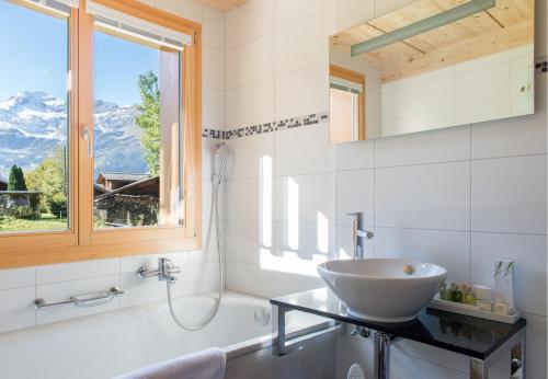 a bathroom with a sink and a tub and a window at Chalet Stella Penthouse Residence in Wengen