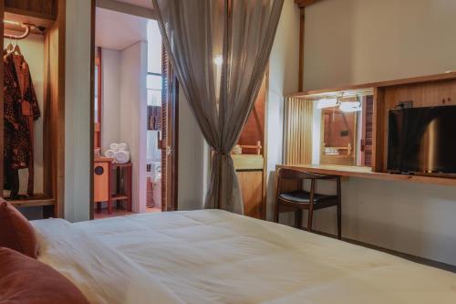 a bedroom with a bed and a desk and a television at Hotel Gahn Khao Lak in Khao Lak