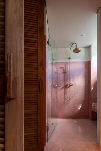 a bathroom with a shower with a glass door at Hotel Gahn Khao Lak in Khao Lak