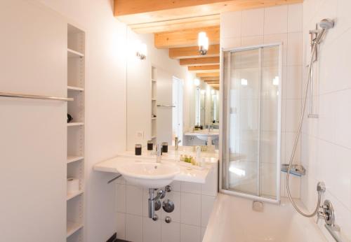 La salle de bains blanche est pourvue d'un lavabo et d'une douche. dans l'établissement Chalet Wyssbirg, à Wengen