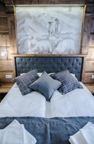 a bed with pillows and a painting of sheep at Sielanka Apartamenty SPA in Białka Tatrzanska