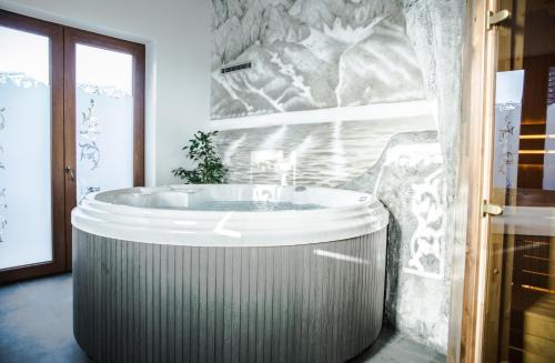 a bath tub in a bathroom with a marble wall at Sielanka Apartamenty SPA in Białka Tatrzanska
