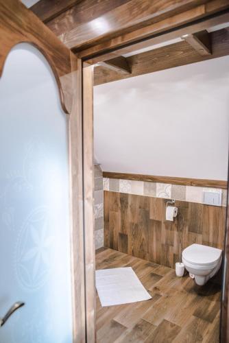 a bathroom with a toilet and wooden walls at Sielanka Apartamenty SPA in Białka Tatrzanska