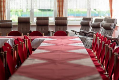 a long table in a room with red chairs at Hotel Krone in Matrei am Brenner