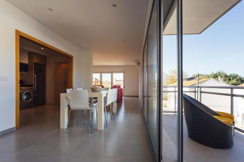 a dining room with a table and white chairs at Muralha - By SCH in Nazaré