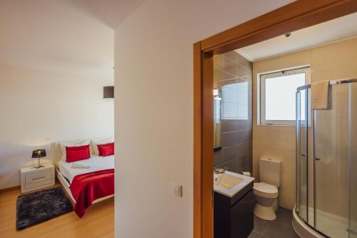 a bedroom with a bed and a bathroom with a sink at Muralha - By SCH in Nazaré