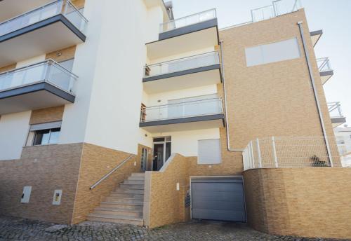 an apartment building with stairs and a garage at Muralha - By SCH in Nazaré