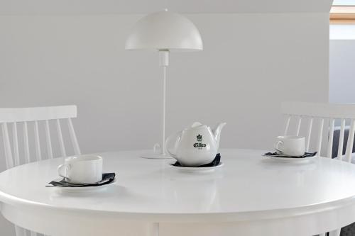 a white table with two tea pots and saucers at GRANO APARTMENTS Gdańsk Motława SPA & Wellness in Gdańsk