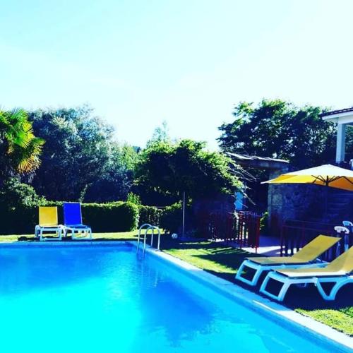 a swimming pool with two lawn chairs and umbrellas at Quinta da Chouza Agroturismo e Enoturismo in Celorico de Basto