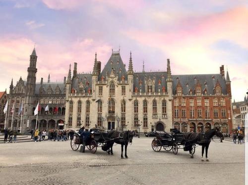 dos carruajes tirados por caballos frente a un gran edificio en BAAN SIAM en Bruges