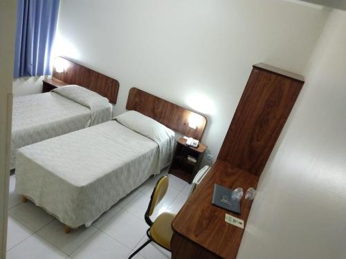 a hotel room with two beds and a desk at Patriarca Hotel in Itapeva