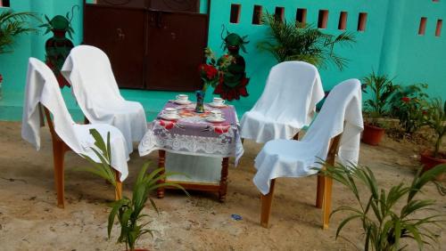 un grupo de sillas blancas y una mesa con un jarrón. en Vamoose Mangrove Pitta, en Kendrāparha