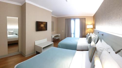 a hotel room with two beds and a mirror at Enotel Lido - All Inclusive in Funchal