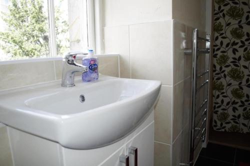 a white sink in a bathroom with a window at Leith City Centre Guesthouse Apartment in Edinburgh