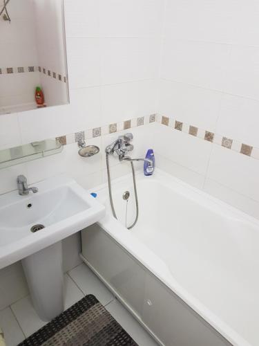a white bathroom with a sink and a shower at Bishkek Sunny Apartment in the center in Bishkek