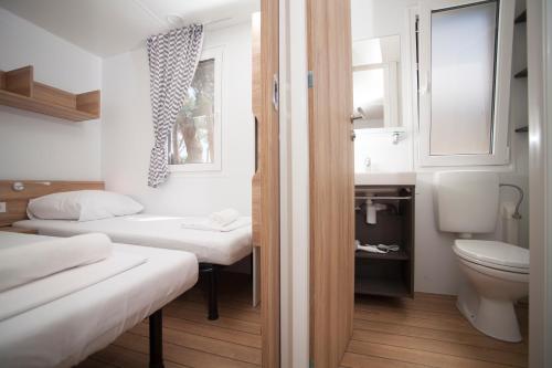uma pequena casa de banho com 2 camas e um WC em Mediteran Travel Mobile Homes in Camping Terme Čatež em Brežice