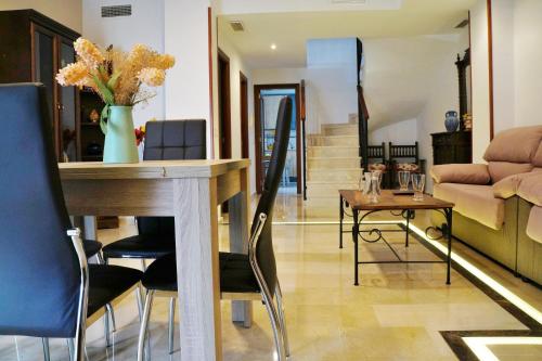a living room with a table with a vase of flowers at Dúplex Centro Parking Ronda in Ronda