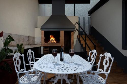a table and chairs with wine glasses and a fireplace at Gem of a House by Homie in Funchal