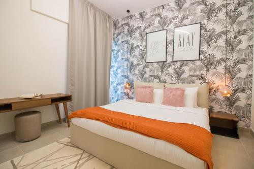 ドバイにあるIn Healthcare City, Newly Furnished, 1BR Azizi Aliyahのベッドルーム1室(オレンジ色の毛布と壁紙を使用したベッド1台付)