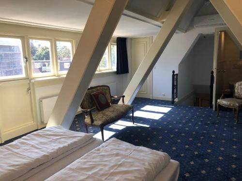 a room with a bed, chair, and desk in it at Hotel De Gulden Waagen in Nijmegen