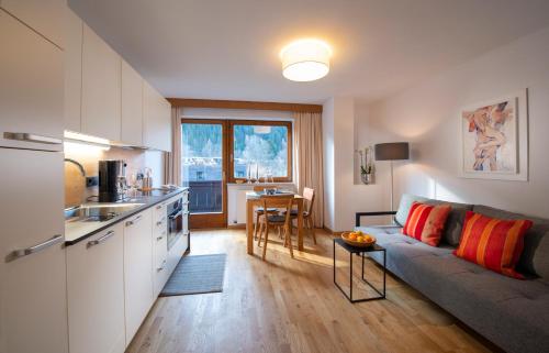 eine Küche und ein Wohnzimmer mit einem Sofa und einem Tisch in der Unterkunft Appartements Falkner Dorli in Oetz