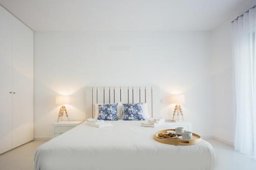 een witte slaapkamer met een wit bed en een dienblad bij Janelas de Salir - By SCH in Salir de Porto